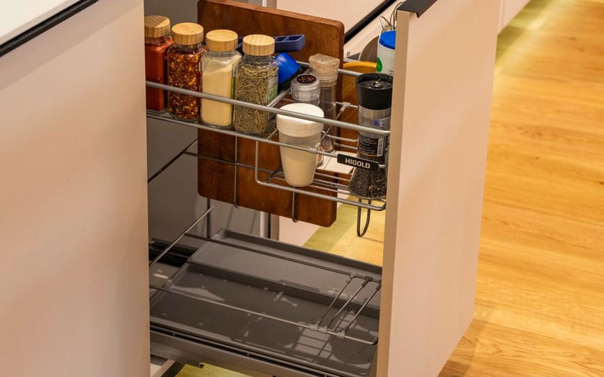 Moderne Küche mit ausziehbarem Gewürzregal, bunten Gewürzen und einem Holzschneidebrett.