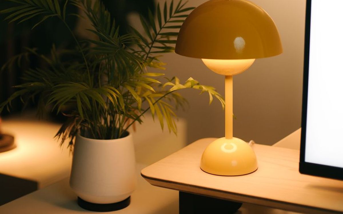 Warmes Licht mit stylischer Lampe und Pflanze auf einem modernen Schreibtisch.