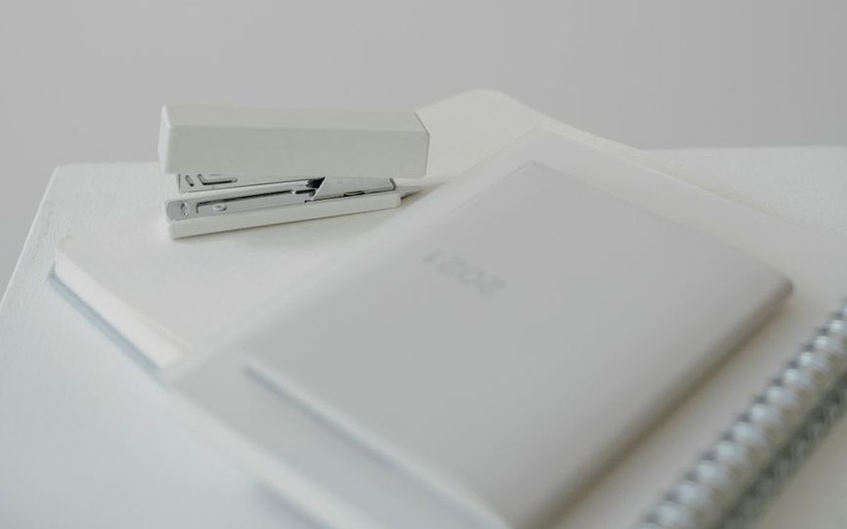 Aufgeräumter heller Schreibtisch mit Notizbüchern und wenigen Arbeitsmaterialien